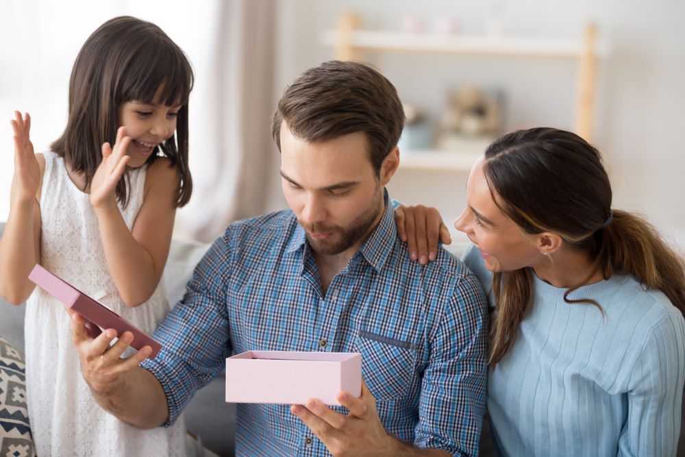 Un papa ouvrant le cadeau de ses enfants