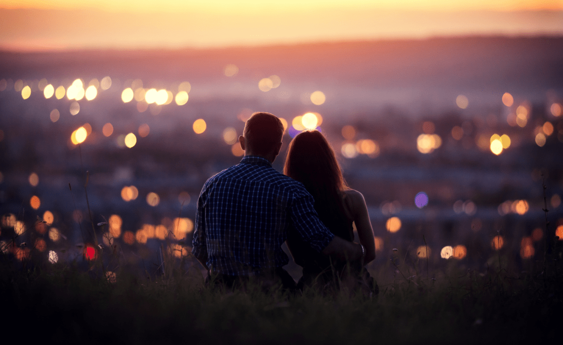 Couple qui admire enlacés une ville sous un coucher de soleil