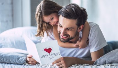 Un père et sa fille qui ouvrent ensemble la carte de Fête des pères que la petite fille a réalisé pour son papa