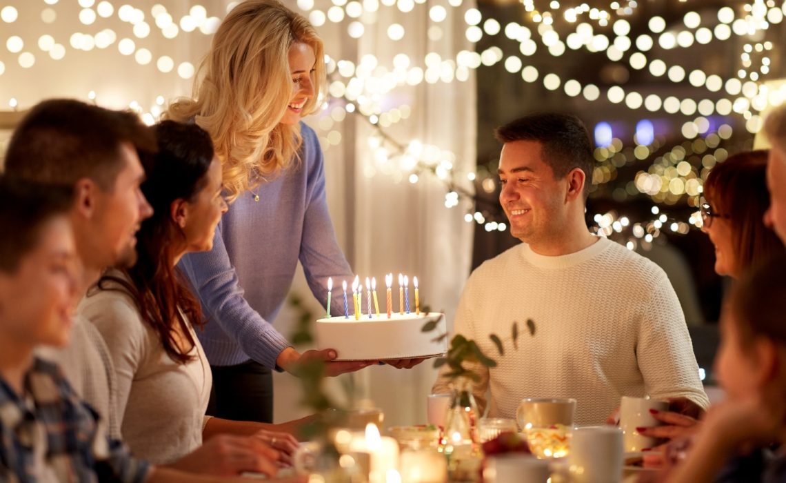 Un homme fêtant son anniversaire avec ses amis et qui s'apprête à souffler sur son gâteau d'anniversaire
