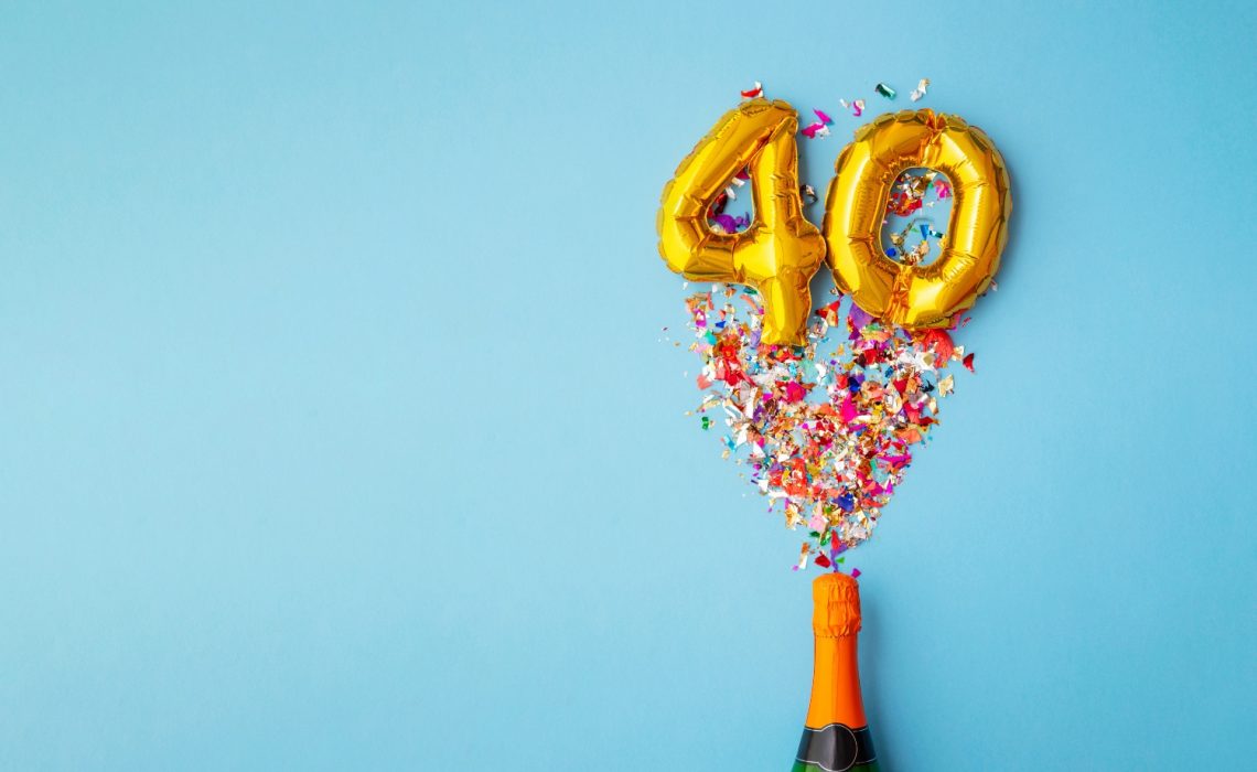 Bouteille de champagne qui explose avec des confettis et des ballons qui forment le nombre 40