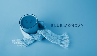 Un mug entouré d'une écharpe bleue avec écrit à côté : le Blue Monday, le jour le plus triste de l'année