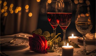 Deux verres d'alcool et une rose rouge posés sur une table de restaurant