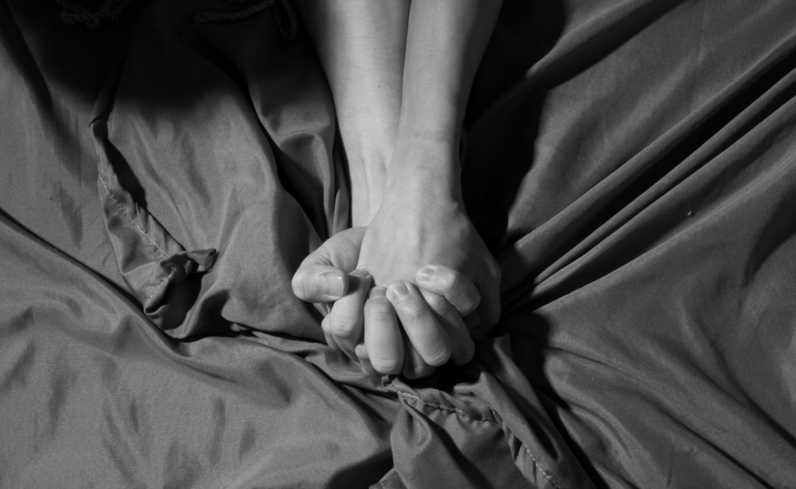 Mains enlacées dans un lit