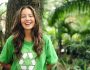 Adolescente qui sourit, posée contre un arbre et portant un t-shirt vert recyclage