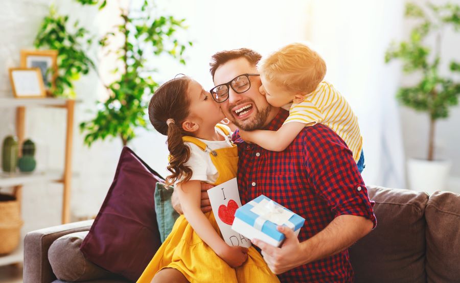 Des enfants en train de faire des bisous et offrir des cadeaux à leur papa pour la fête des pères