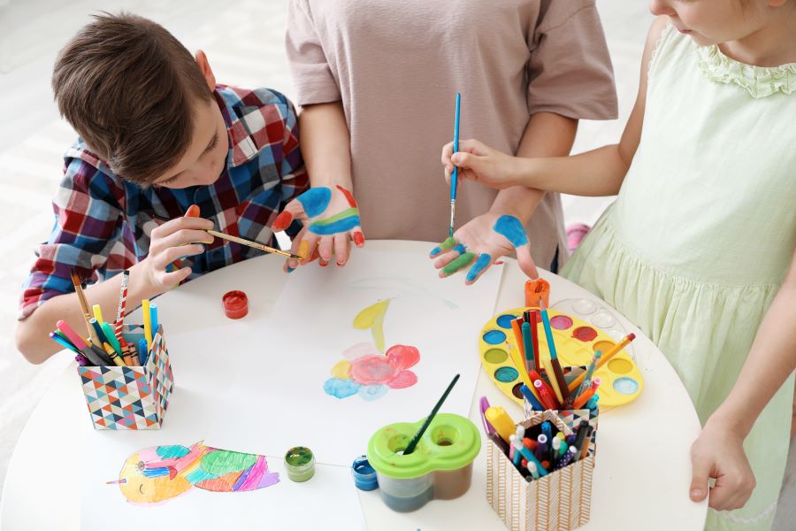 Des enfants qui se mettent de la peinture sur les mains pour préparer un cadeau