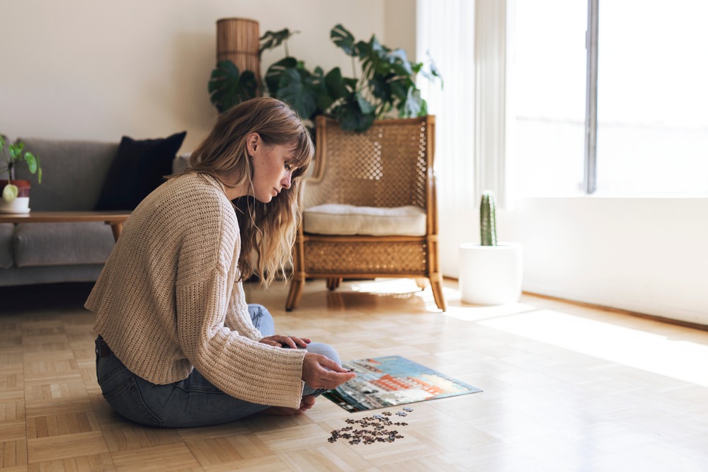 Femme assise dans son salon qui réfléchit devant un puzzle photo personnalisé