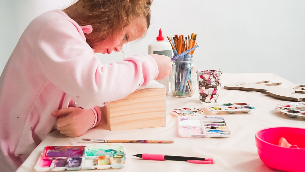 Une petite fille en train de peindre une boîte