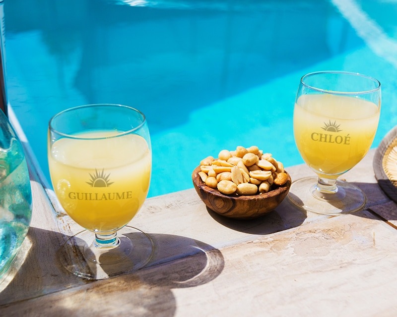 Verres à Ricard gravés posés à côté d'un petit bol de cacahuètes et d'une piscine