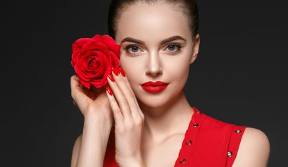 femme tenant une rose éternelle rouge près de son visage