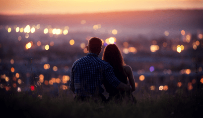 Couple qui admire enlacés une ville sous un coucher de soleil