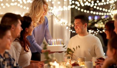 Un homme fêtant son anniversaire avec ses amis et qui s'apprête à souffler sur son gâteau d'anniversaire