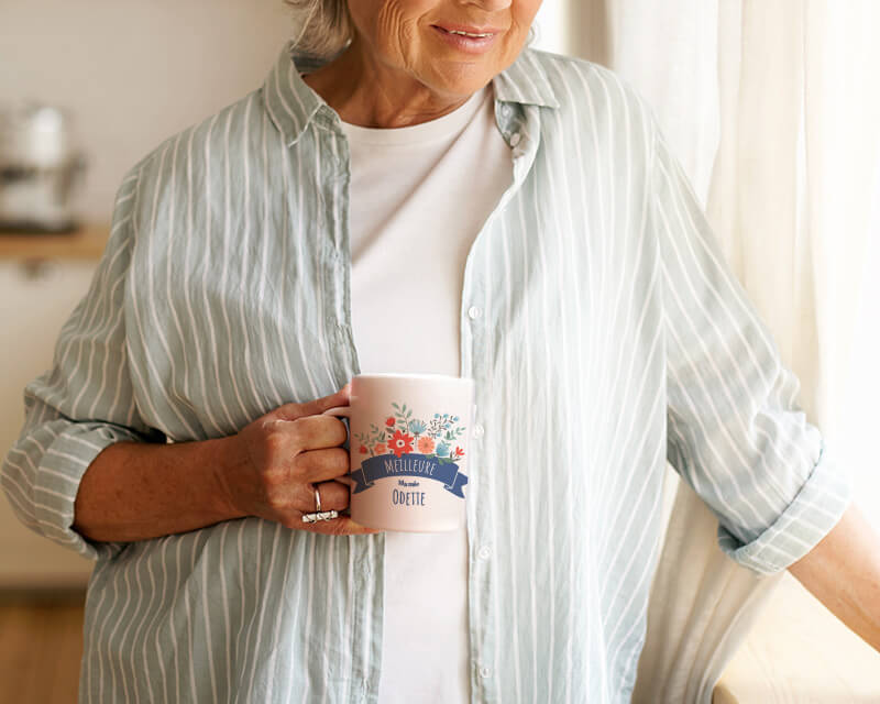 Cadeau Fête des mamies : mug blanc personnalisé 'Mamie fleurie' avec motifs floraux, accompagné de biscuits emballés, sur table en bois.
