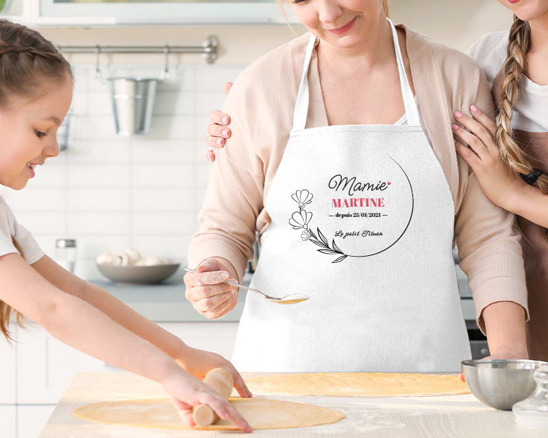 Idée cadeau Fête des mamies : détail du tablier personnalisé 'Mamie depuis [année]' avec illustration florale, soulignant la qualité de l'impression.