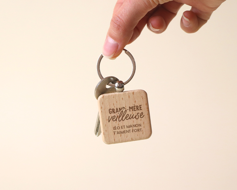 Cadeau Fête des mamies : porte-clés en bois carré gravé 'Mamie' personnalisé par un prénom, attaché à un trousseau de clés sur table en bois.