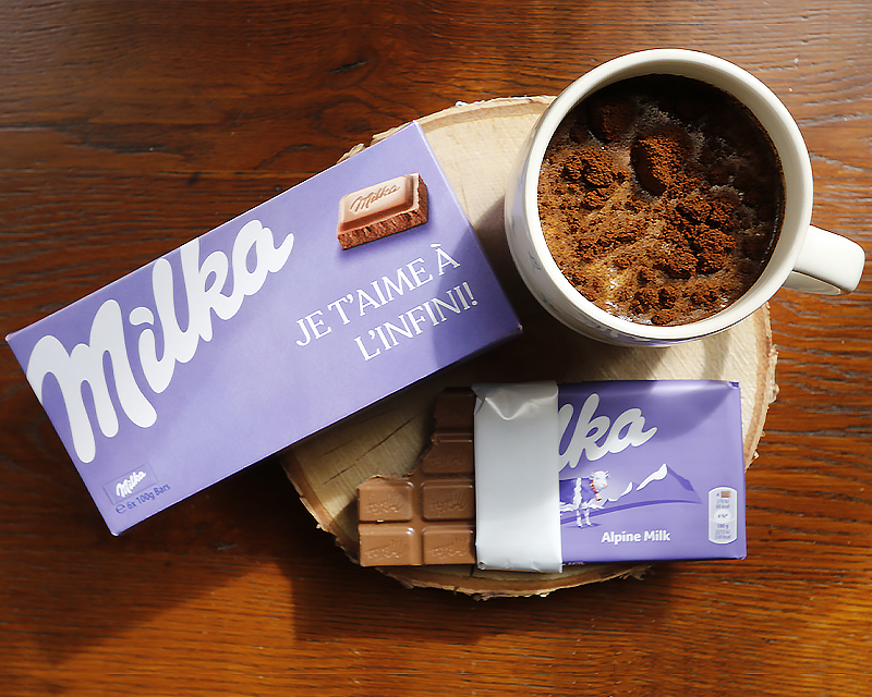 Coffret Milka personnalisé, posé à côté d'une tablette de chocolat Milka et d'une tasse de chocolat chaud